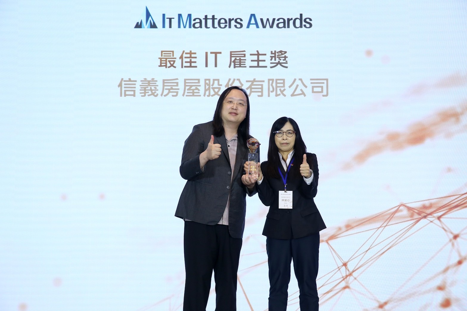 信義房屋獲「最佳IT雇主獎」，由總經理陳麗心（右）從數位發展部長唐鳳手中接過獎座。